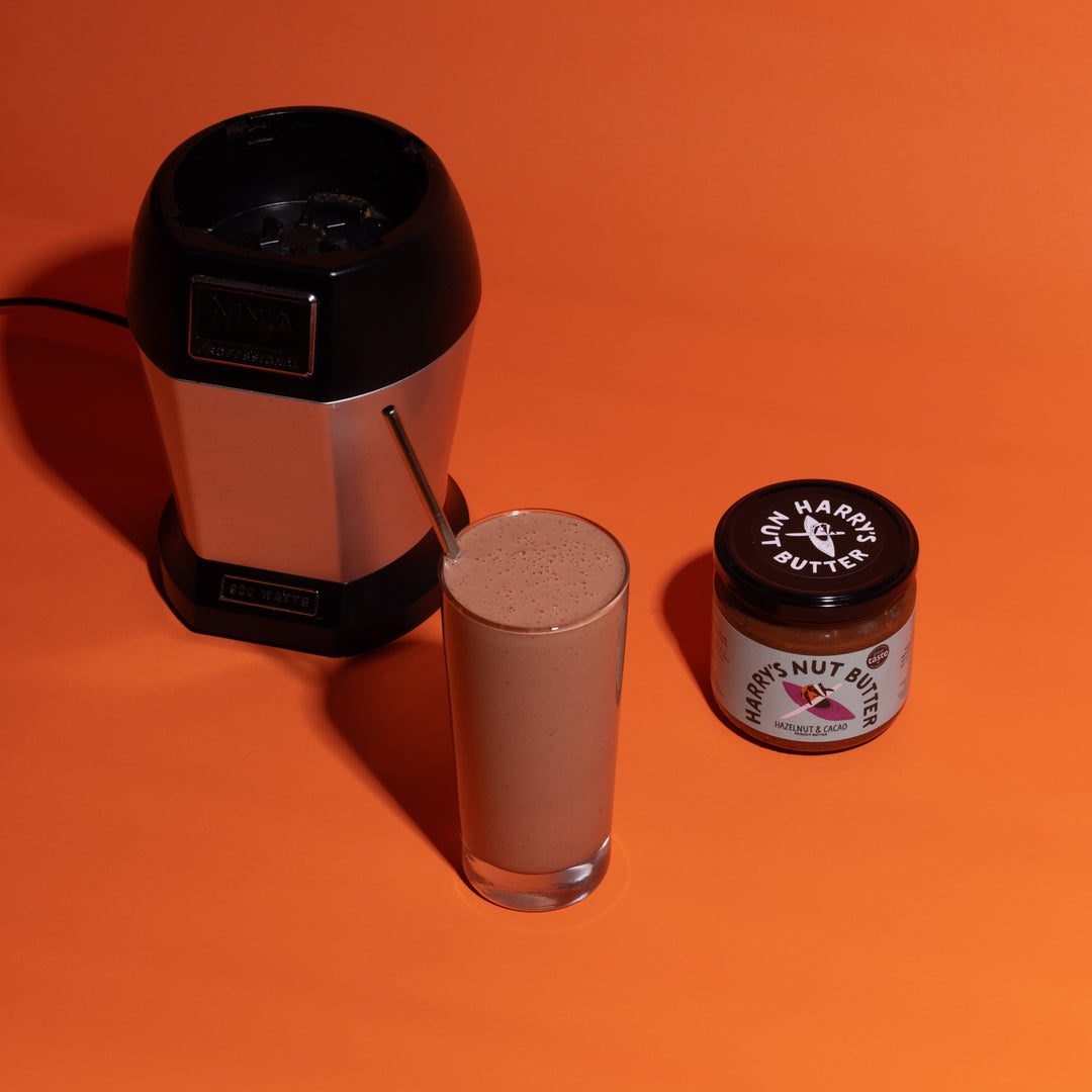 A jar of Harry's Nut ButterHazelnut and Cacao Beside a smoothie and smoothie maker